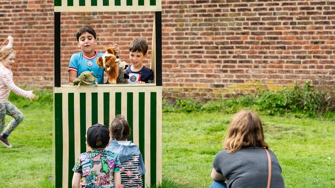 Two children put on a show in the mini stiped 'puppet theatre'.